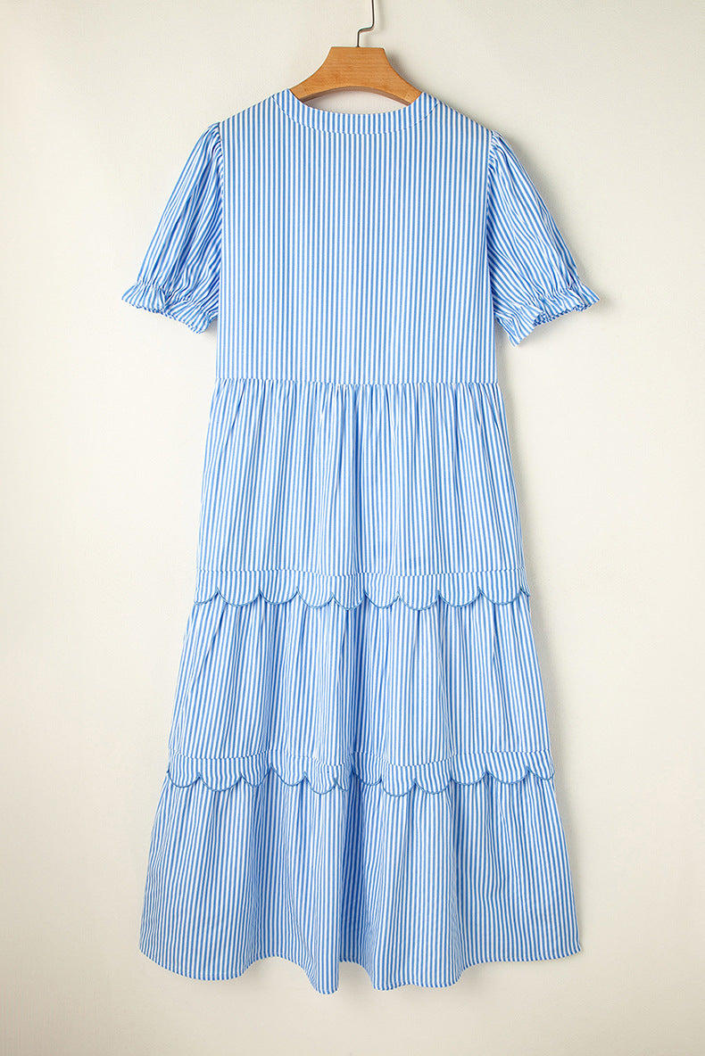Blue and white striped dress on a wooden hanger against a beige background