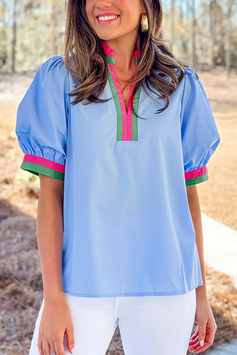 Woman wearing a light blue blouse with colorful trim in an outdoor setting