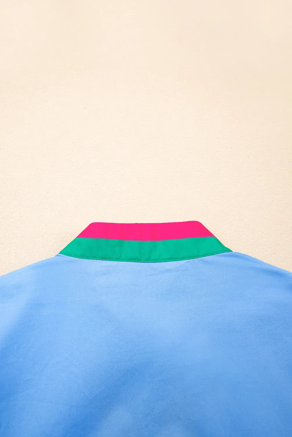 Blue shirt with a colorful collar against a beige background
