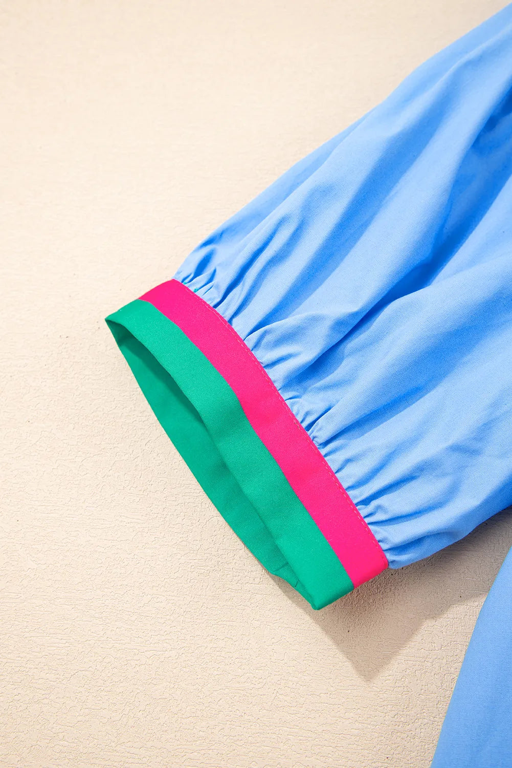 Close-up of a blue garment with colorful trim on a beige background