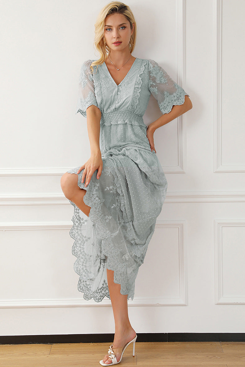 Woman wearing a light blue lace dress against a white wall.