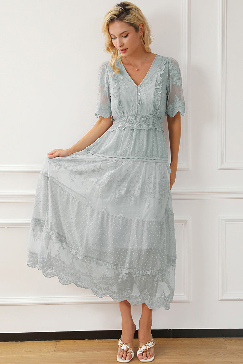 Woman wearing a light blue lace dress against a white wall.
