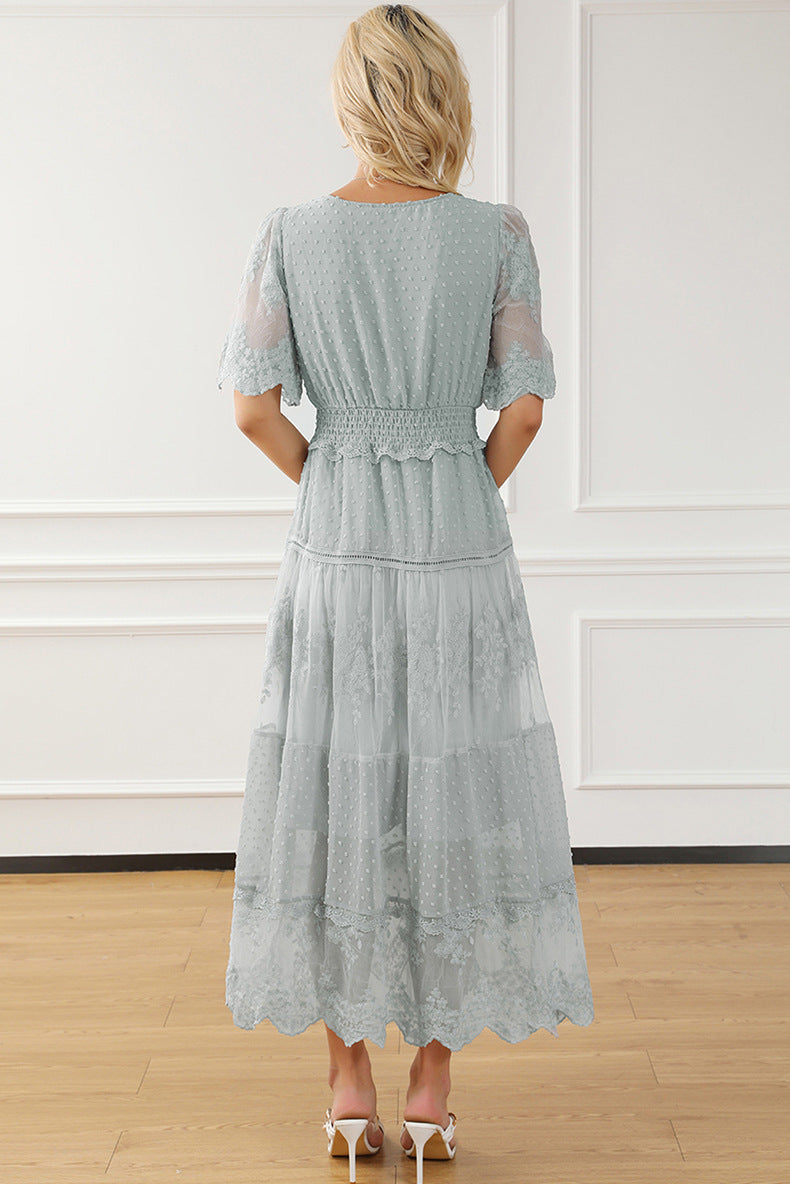 Woman wearing a light blue lace dress in a room with white walls and wooden floor.
