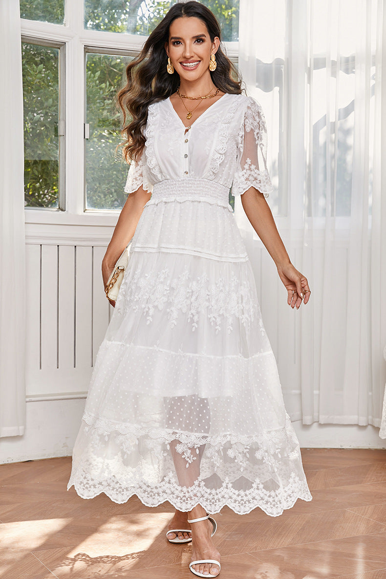Woman wearing a white lace dress in a bright room with large windows.