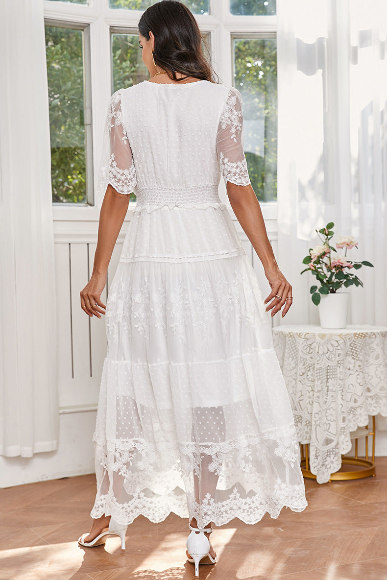 Woman wearing a white lace dress in a bright room with large windows.
