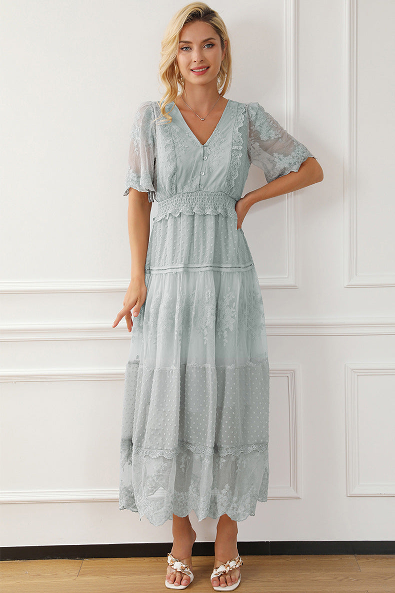 Woman wearing a light blue lace dress standing against a white paneled wall.