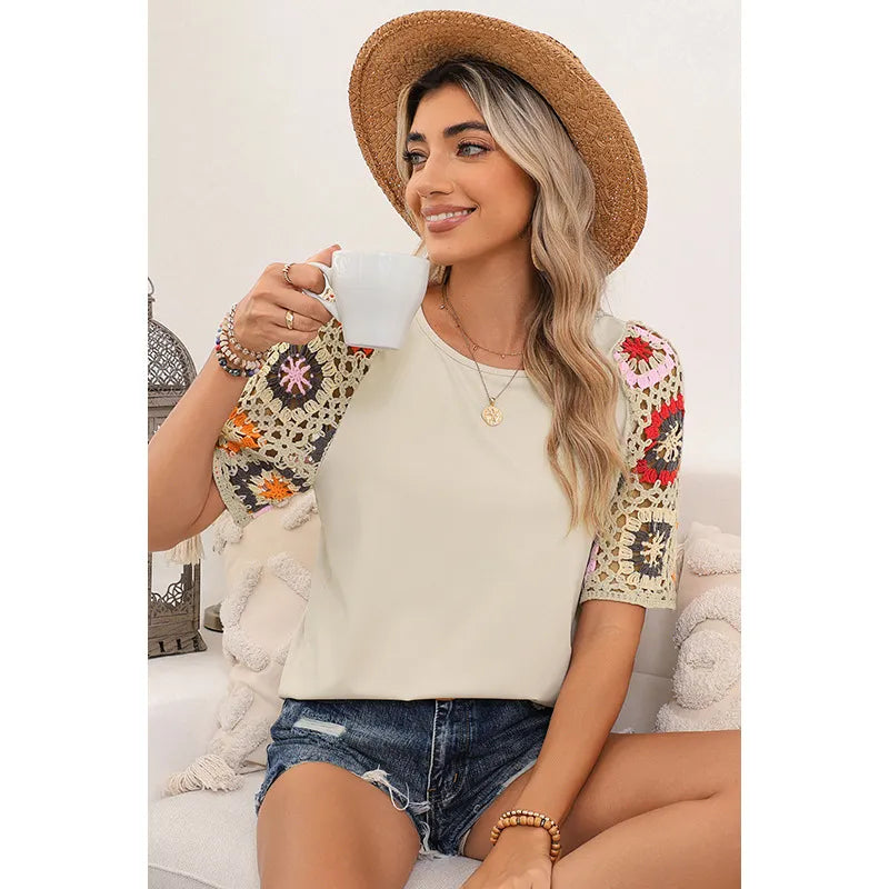 Woman sitting on a couch wearing a floral sleeve top and straw hat, holding a white mug.