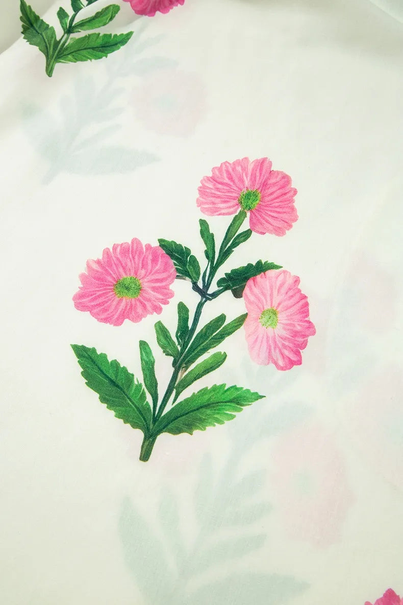 Embroidered pink flowers with green leaves on a white fabric background