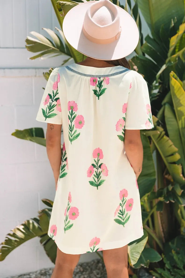 Person wearing a floral dress with a white hat in a tropical setting
