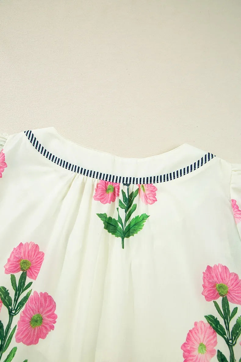 White blouse with pink floral embroidery on a beige background
