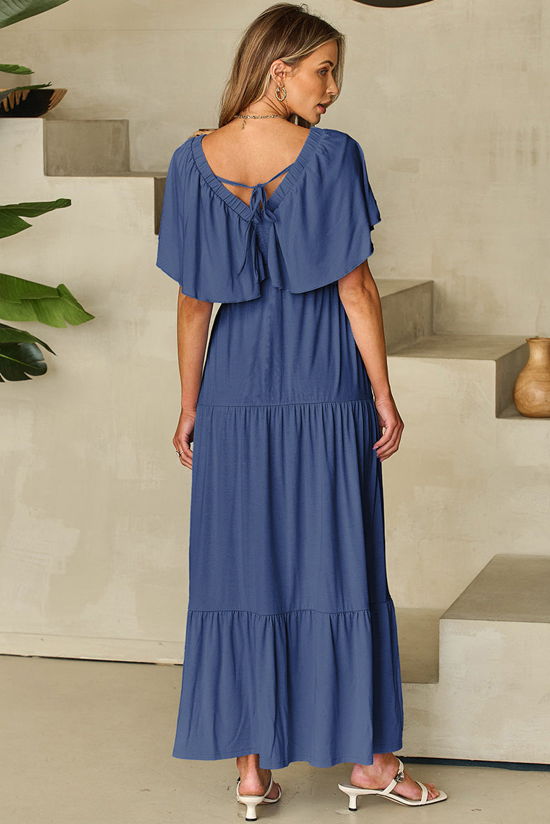 Woman wearing a blue dress standing in a minimalistic indoor setting.