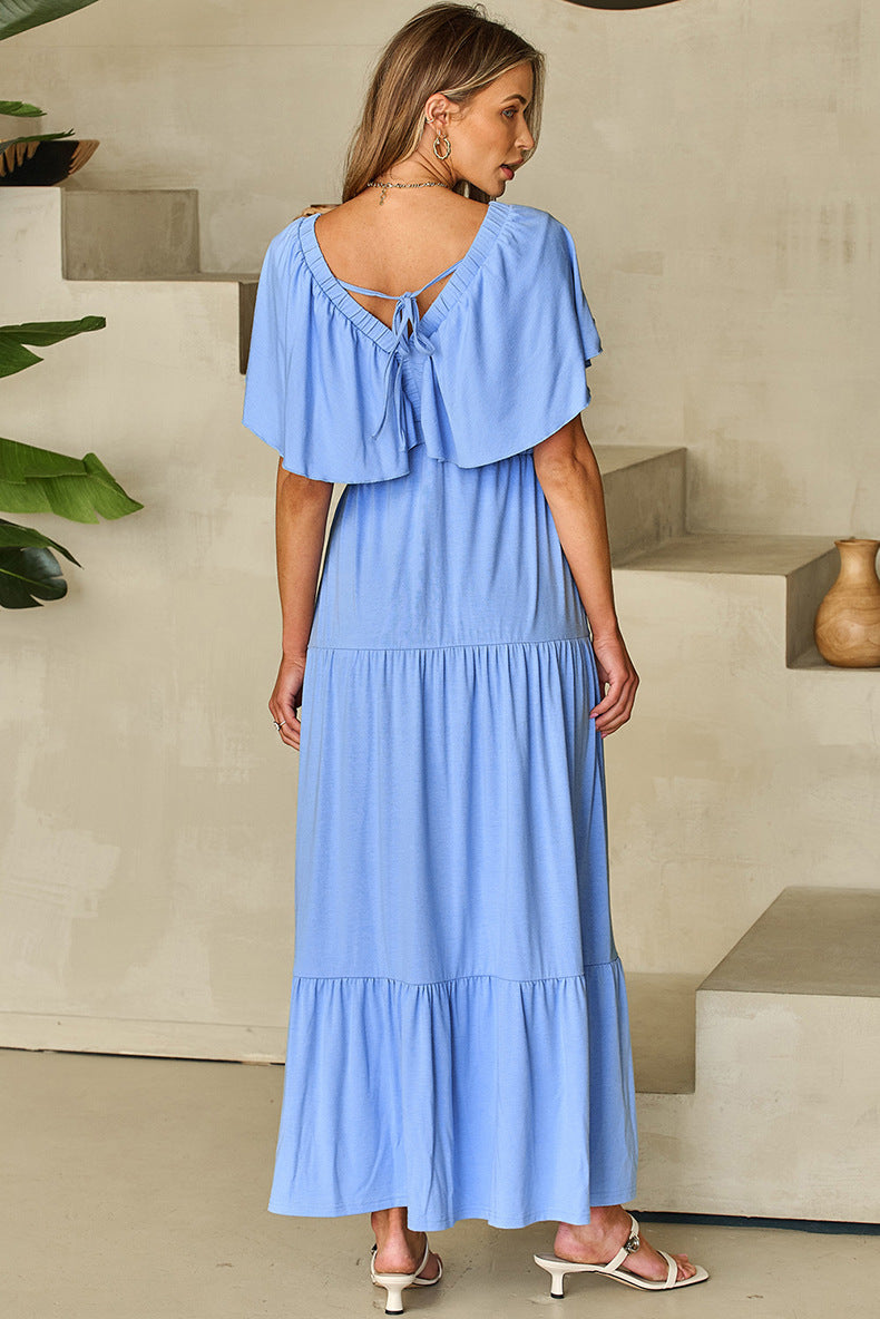 Woman wearing a blue dress with ruffled sleeves in an indoor setting.