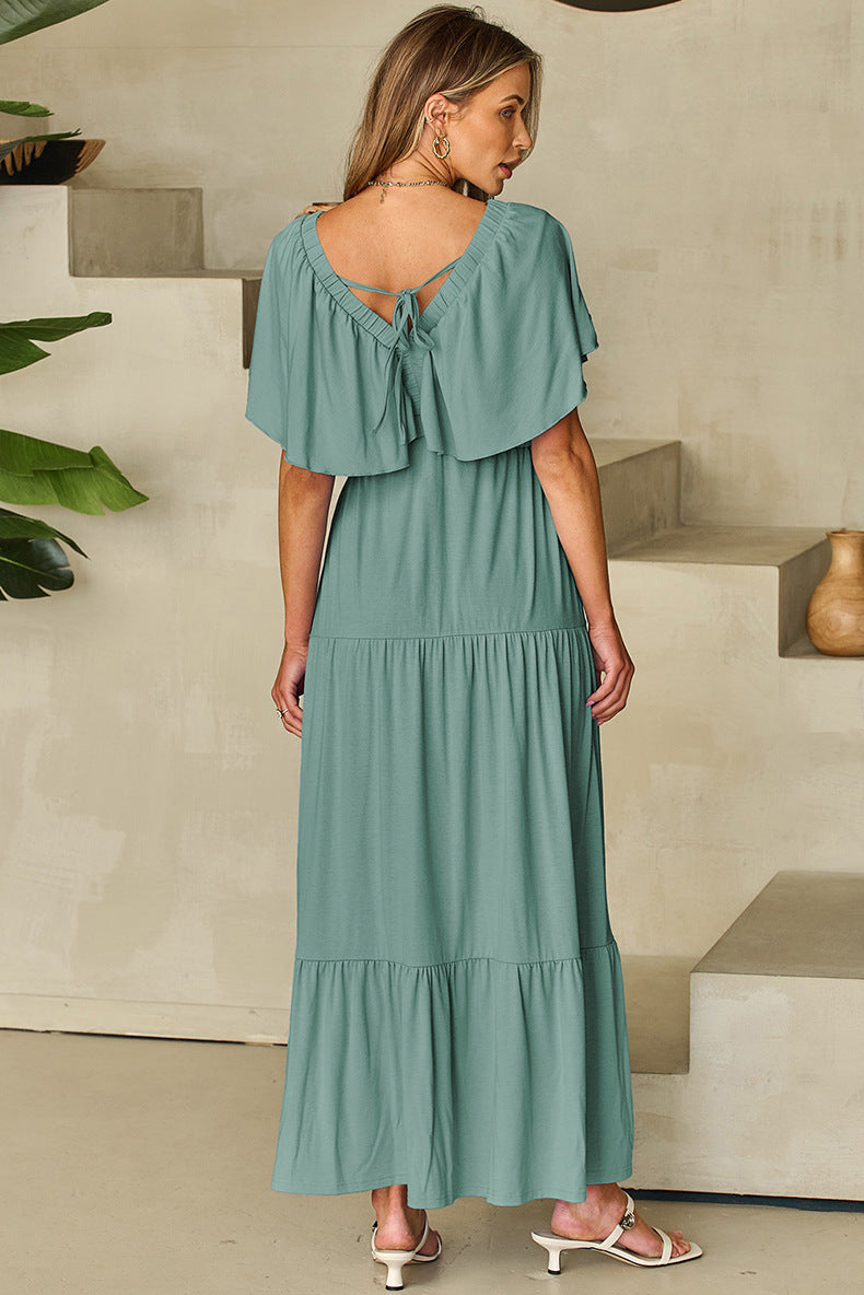 Woman wearing a green dress with ruffled sleeves and tiered skirt in an indoor setting.