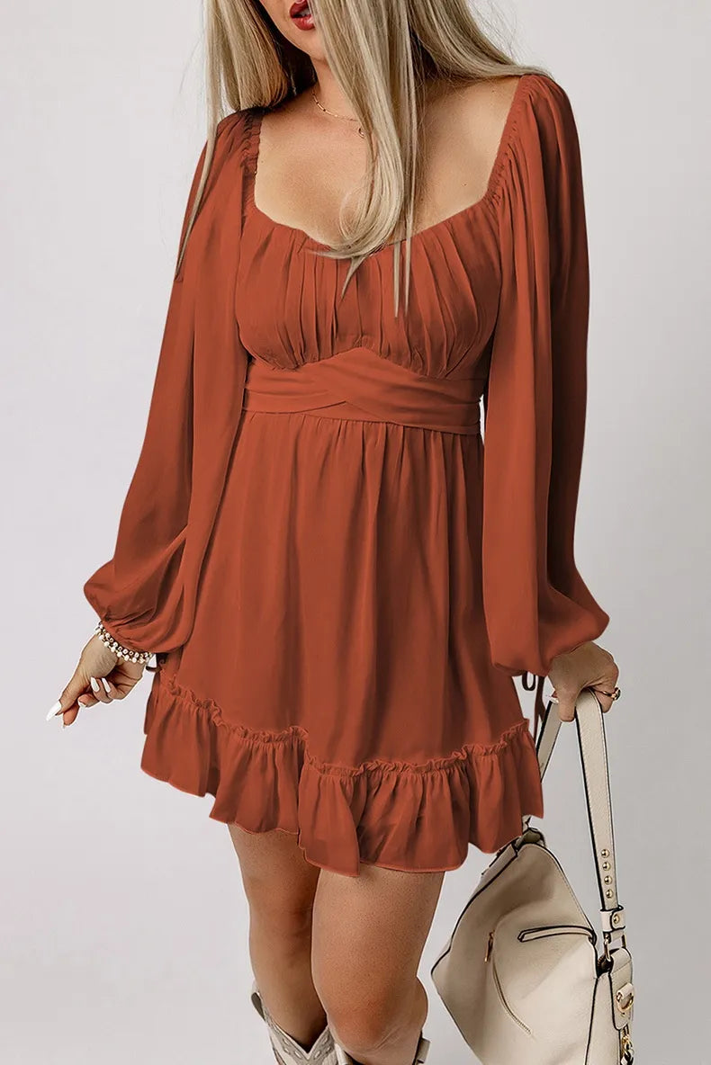 Woman wearing a rust-colored dress with long sleeves and a beige handbag on a light gray background