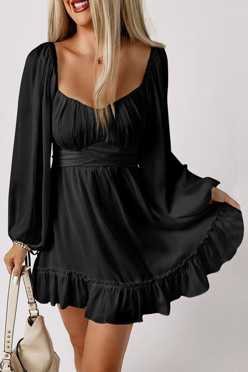 Woman wearing a black dress with long sleeves and ruffled hem on a white background