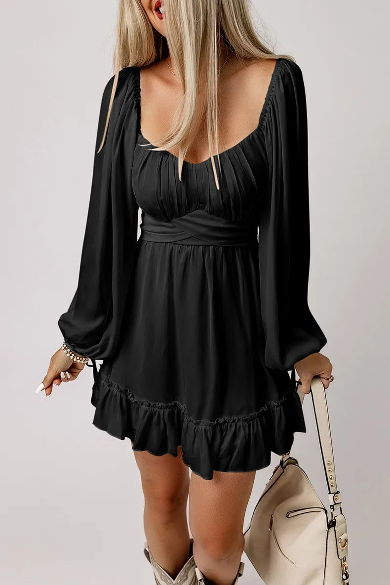 Woman wearing a black dress with long sleeves and ruffled hem, holding a beige handbag.