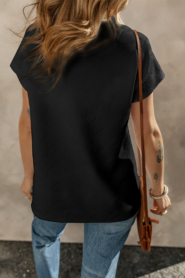 Person wearing a black sleeveless top and blue jeans, holding a brown leather bag against a neutral background