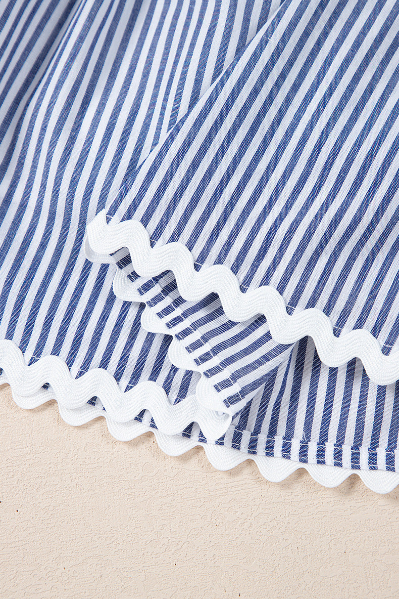Close-up of a blue and white striped fabric with scalloped edge on a beige background